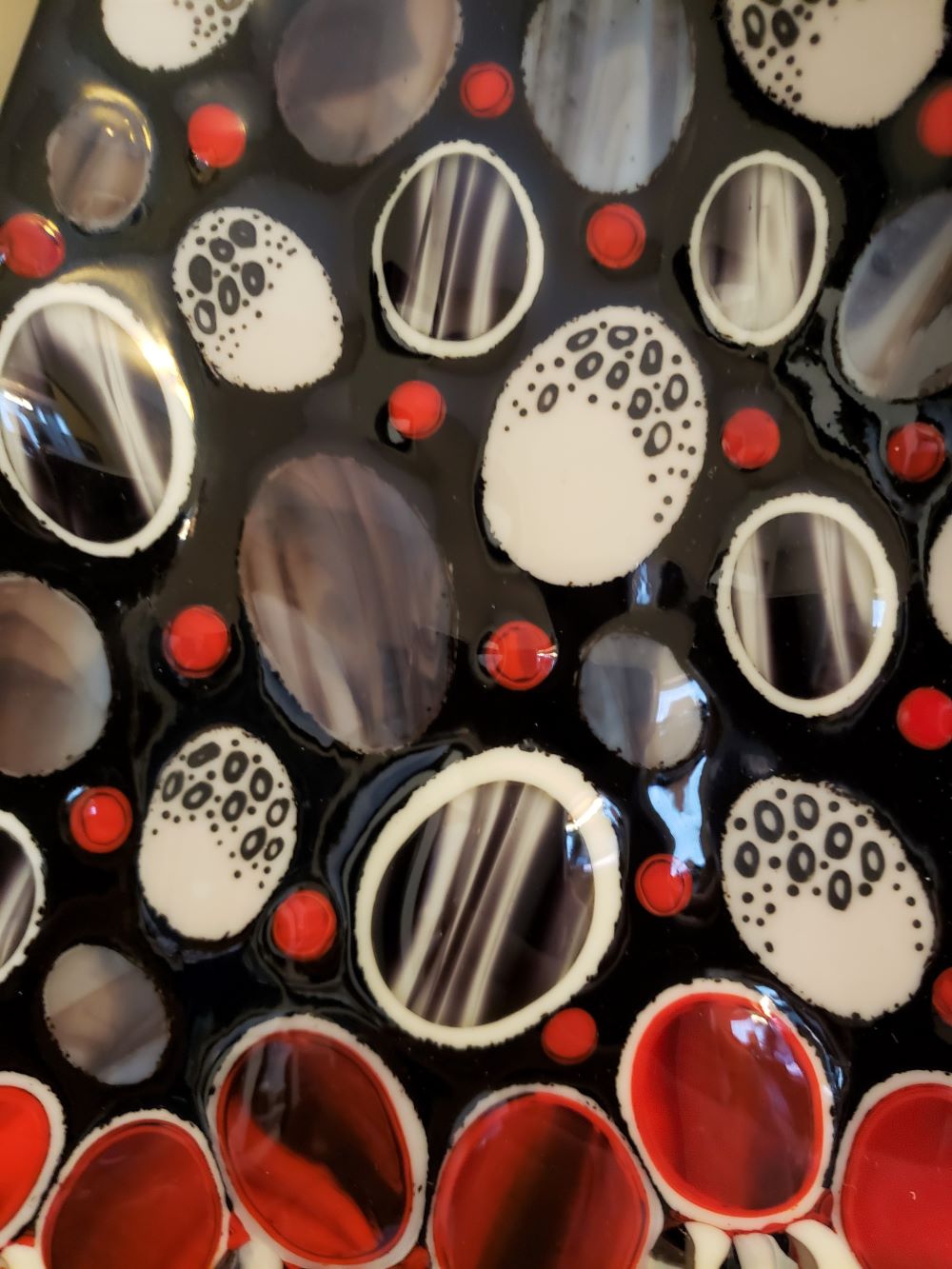 close up of detail of glass wall art that shows ther red black and white design