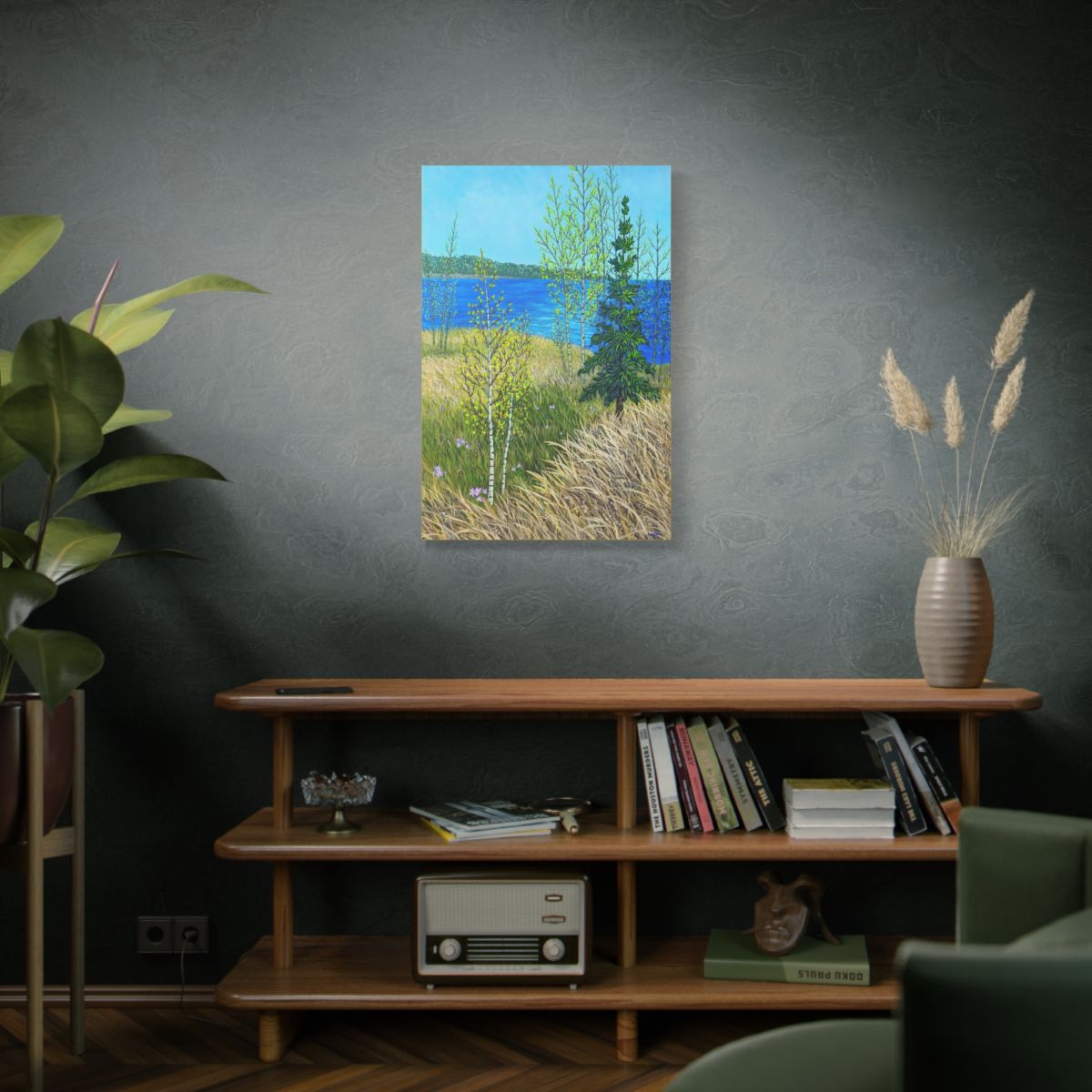 Painting of a landscape with a lake and trees on a wall above a wooden shelf with books and decor.
