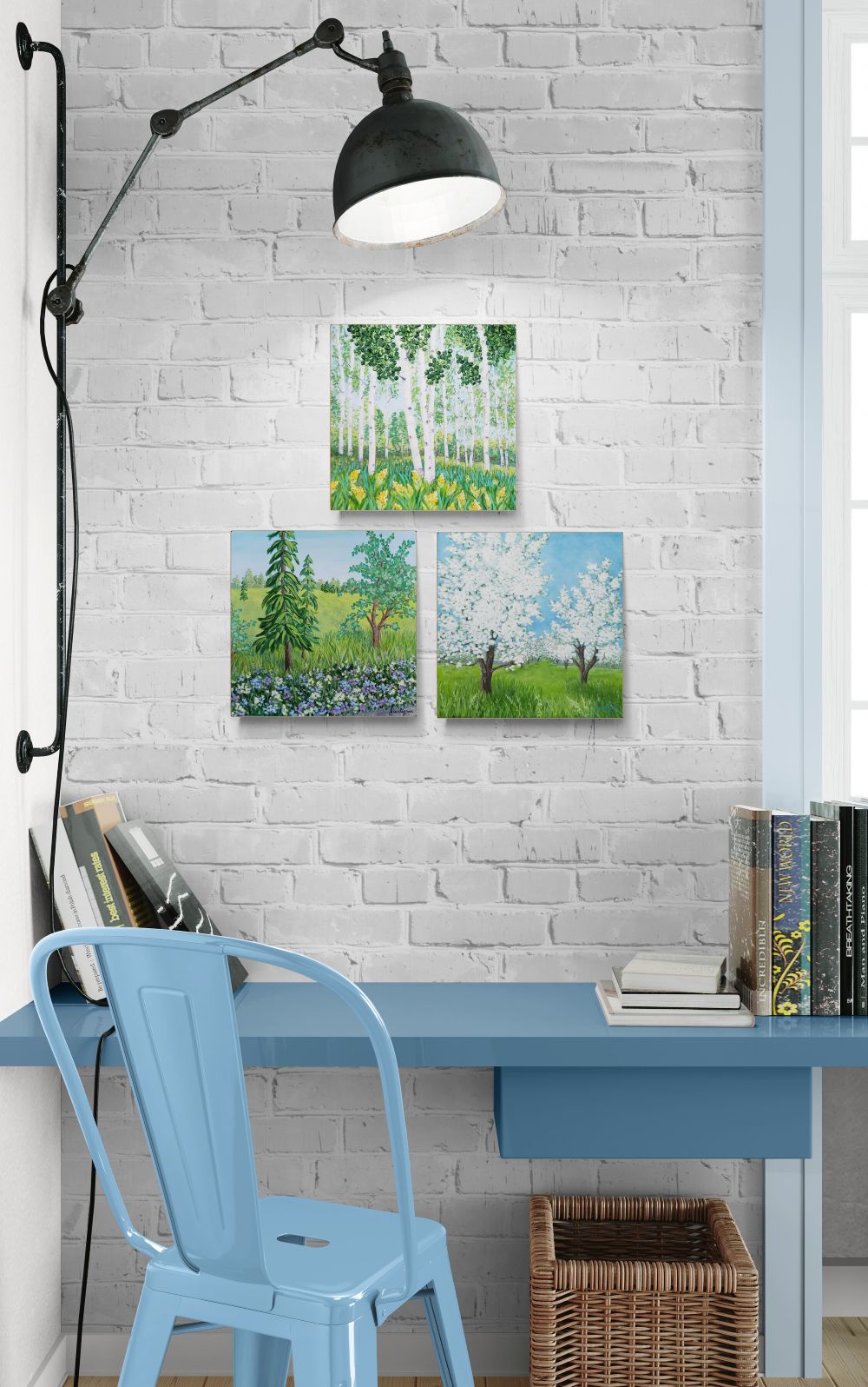 cluster of 3 small paintings of trees shown together on wall by a desk