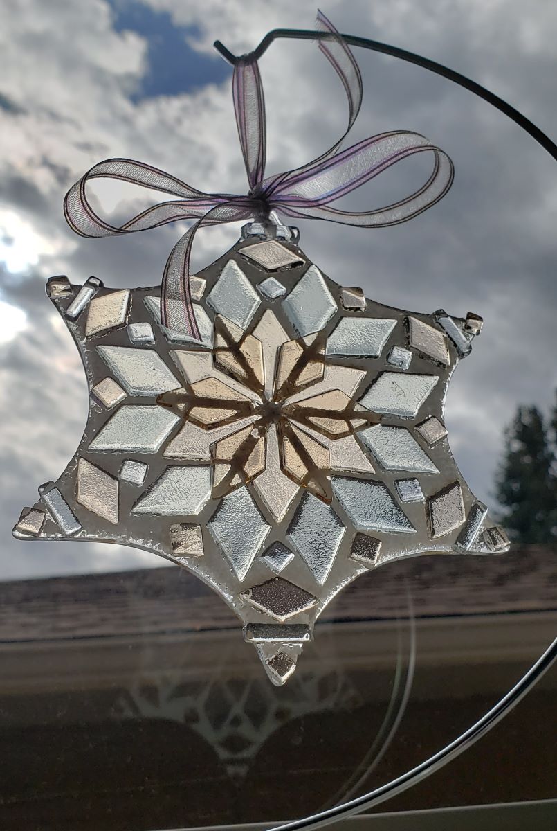 Pink champagne colored glass ornament shown in window