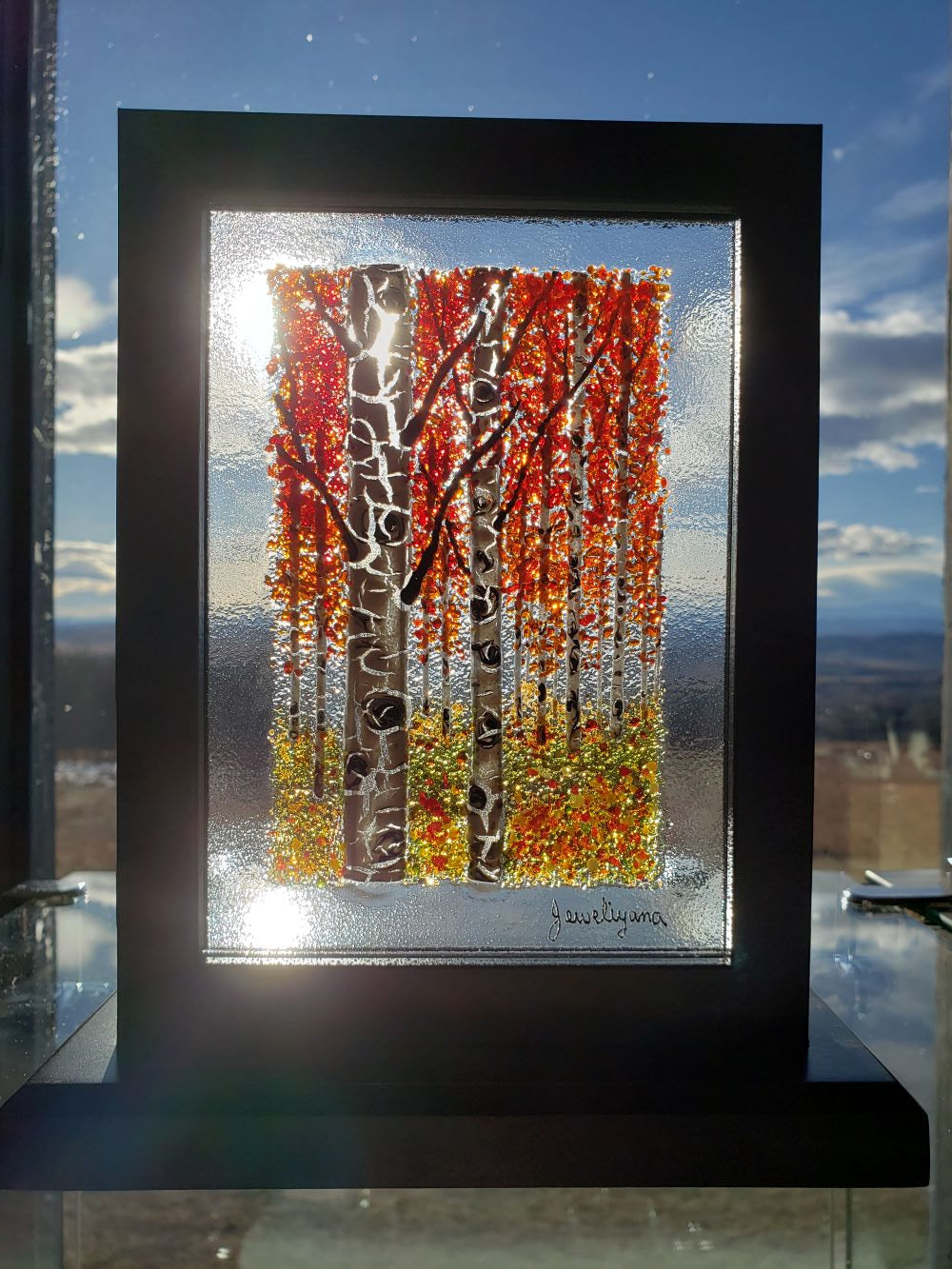 red birch trees made of glass shown in a window with natural back lighting